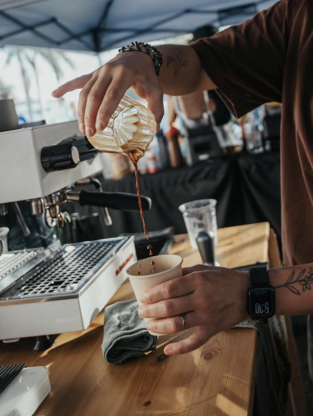 Barista sirviendo un espresso recién colado en una taza, junto a la máquina de café